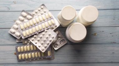 Tahta bir masanın üzerinde çeşitli ilaç şişeleri ve kabarcıklar var..