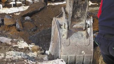 İnşaat işçileri, toprağa hendek kazmak için ağır makineler kullanıyorlar..