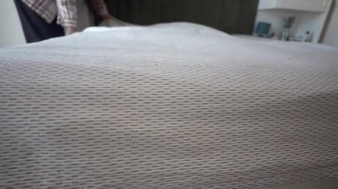Genç bir kadın sabahın erken saatlerinde yatağını yapıyor. ,