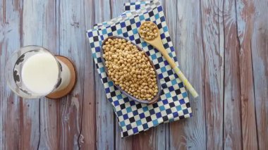 Soya fasulyesi bir kasenin içinde masanın üzerindeki bir bardak sütün yanında sergilenir..