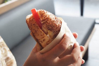 Bir insan rengarenk malzemelerle dolu yeni yapılmış bir sandviçi sever..