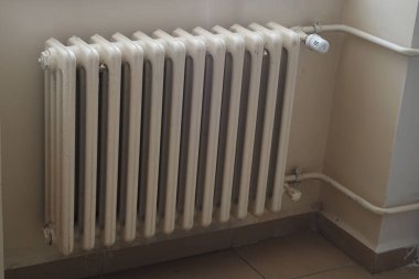 Isınmak için beyaz metal bir radyatör duvara dayanıyor..