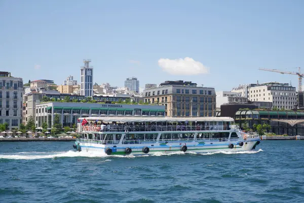 Bir tekne şehir binalarının yanındaki suda süzülürken yolcuları taşır..