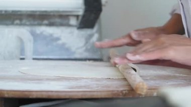 Bir şef, her yerde un olan sıcak bir mutfakta ustalıkla hamur toplar..