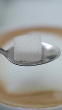 Kaşıkla dengelenmiş, kahveye hazır şeker küpünün yakın çekimi..