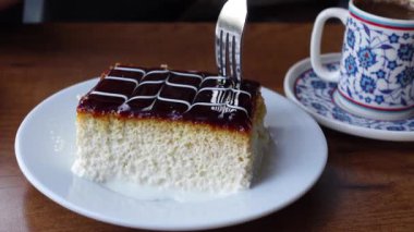 Parlak krema ve kremayla kaplı bir dilim ıslak pastanın tadını çıkarıyorum..