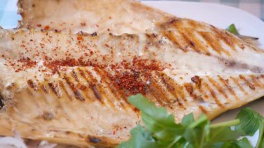 Taze otlarla servis edilen baharatlı ızgara balık..