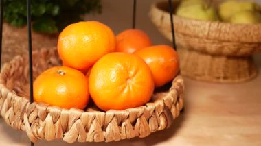 Parlak portakallar ahşap bir masada el dokuması bir sepetin içinde..
