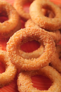 Çıtır çıtır, altın sarısı soğan halkaları renkli bir tabakta dizilmiş..