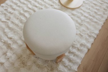 Yumuşak yuvarlak bir tabure şık bir oturma odasındaki yumuşak bir halıya dayanır..