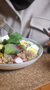 Öğle yemeği için yumurta, yeşillik ve tahıllı besleyici bir salatanın tadını çıkarıyorum..