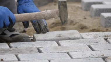 Bir kişi arka bahçedeki peyzaj projesi için taşları dikkatlice yerleştiriyor..