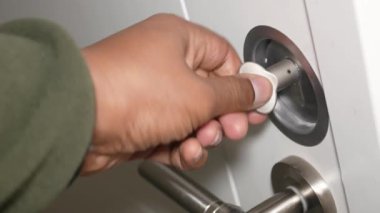Bir el, temiz ve çağdaş bir ortamda kapı kilidine anahtar sokuyor..