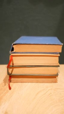 Renkli dikenleri olan çeşitli eski kitaplar ahşap bir yüzeyde duruyor..