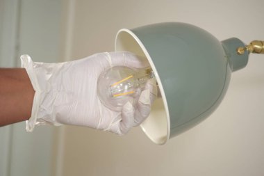 Bir insan içeride eldiven takarken ampulü değiştiriyor..