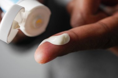 Bir insan, cilt bakımı için parmak ucuna az miktarda krem sürer..