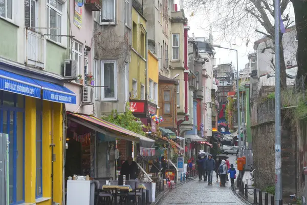 İnsanlar renkli binalar ve dükkanlarla dolu büyüleyici bir sokakta yürüyorlar..