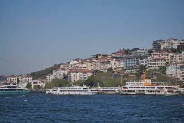 İstanbul 'daki yemyeşil tepelerin yakınındaki rıhtım boyunca tekneler demirli..