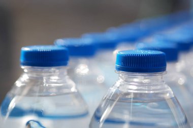 Masaya dizilmiş mavi kapaklı su şişelerinin yakın çekim görüntüsü.