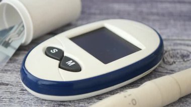 Kullanıcı kan şekeri seviyelerini glikoz ölçer ve kalemle izliyor.