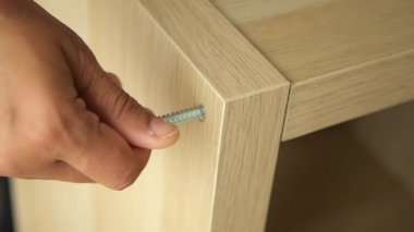 El montaj sırasında ahşap bir mobilyaya vida yerleştiriyor..