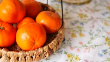 Parlak portakallar renkli çiçeklerle kaplı bir sepetin içinde otururlar..