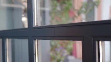 Dışarıda yeşillik olan siyah çerçeveli pencerenin yakın görüntüsü.