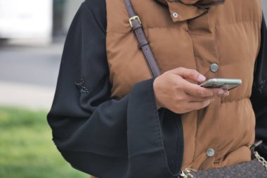 Kişi şık giyinirken akıllı telefona odaklanır..