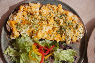 Çırpılmış yumurta ve erimiş peynir. Taze salatayla servis edilmiş tost..