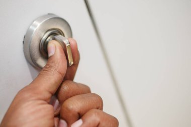 Biri beyaz bir kapıyı açmak için kapı kolunu çeviriyor..
