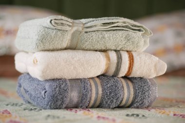 Yumuşak havlular rahat bir odada düzgünce dizilmiş yatağın üzerine serilmiştir..