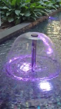 Su zarifçe akarken göz kamaştırıcı bir çeşme parlak ışıklar içerir..