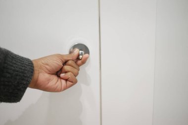 Bir el, minimalist bir alanda yuvarlak bir kapı kolunu tutuyor..