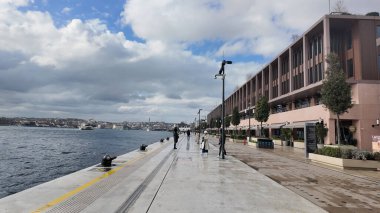 İstanbul 'da nehir kıyısındaki rıhtımda insanlar geziniyor.