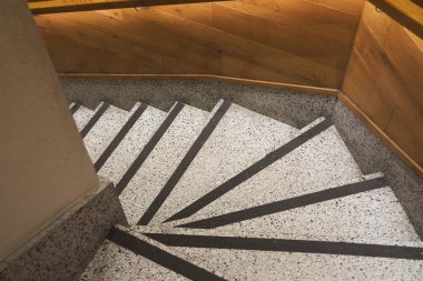 Kapalı bir alanda dokuları ve ışığı olan kıvrımlı merdiven..