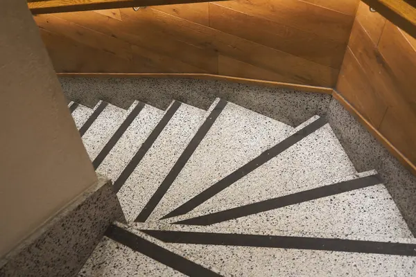 Kapalı bir alanda dokuları ve ışığı olan kıvrımlı merdiven..