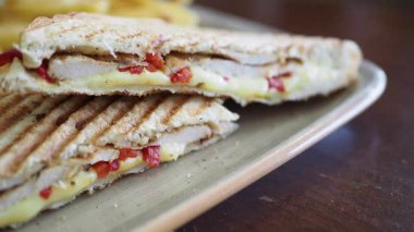 Peynirli ve biberli kızarmış tavuklu sandviçin tadını çıkarıyorum..