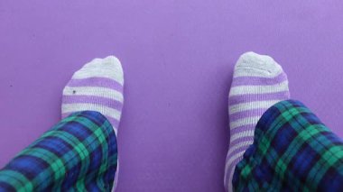 Mor bir paspasın üzerinde rahat pijamalar ve yumuşak çoraplarla evde dinleniyor..
