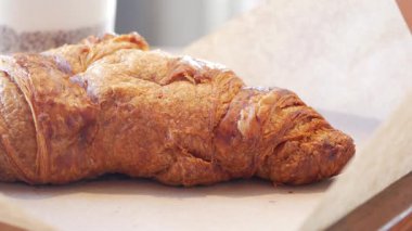 Yeni pişmiş bir kruvasan, rahat bir atmosferde, ahşap bir masada oturur..