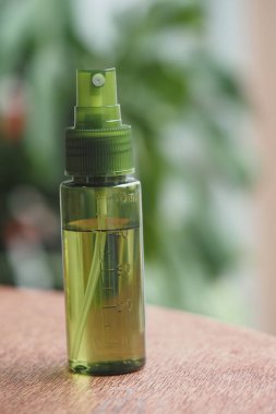 Yeşil bir sprey şişesi ahşap bir masada duruyor..