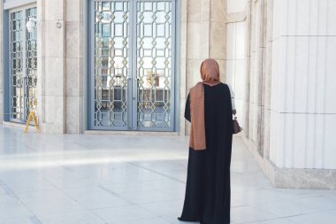 Siyah elbiseli bir kadın alacakaranlıktaki süslü kapıya hayran..