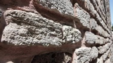 Güneş ışığındaki eşsiz doku ve renkleri vurgulayan taş duvar.