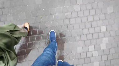 Yağmurlu bir günde ıslak bir şehir caddesinde yürüyen iki kişinin ayak sesleri yankılanıyor..