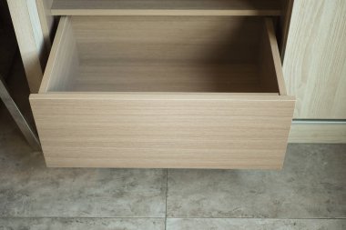 Mutfak dolabından çıkarılan boş ahşap çekmecede tasarımları sergileniyor..