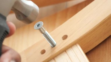 Bu, tahtadaki vidayı sağlamlaştırmak için çekiç kullanan birini gösteriyor..