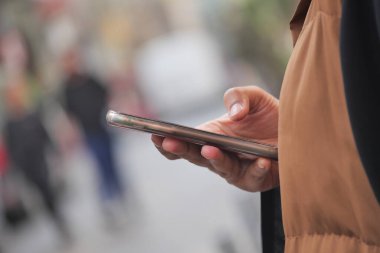 Kalabalık bir caddede yürürken akıllı telefonu kontrol et.