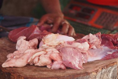 Bir satıcı ahşap bir tahtanın üzerinde çeşitli taze et kesimleri sergiler..