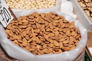 Kuru, kavrulmuş bademlerle dolu büyük bir torba altın-kahverengi tonlarını sergiliyor..