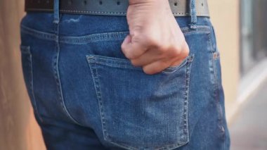 Bir adam elini pantolonunun cebine sokup şehirde yürüyor..