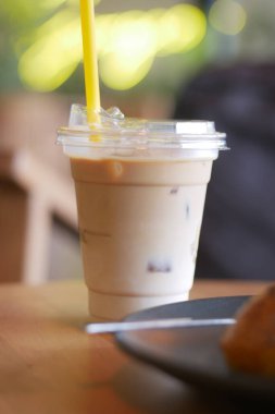 Buzlu içecek bir kafedeki hamur işinin yanındaki ahşap masada oturur..